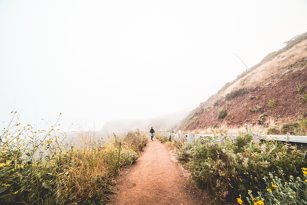 Young Woman Hiking the Mountain Trail in Foggy Weather